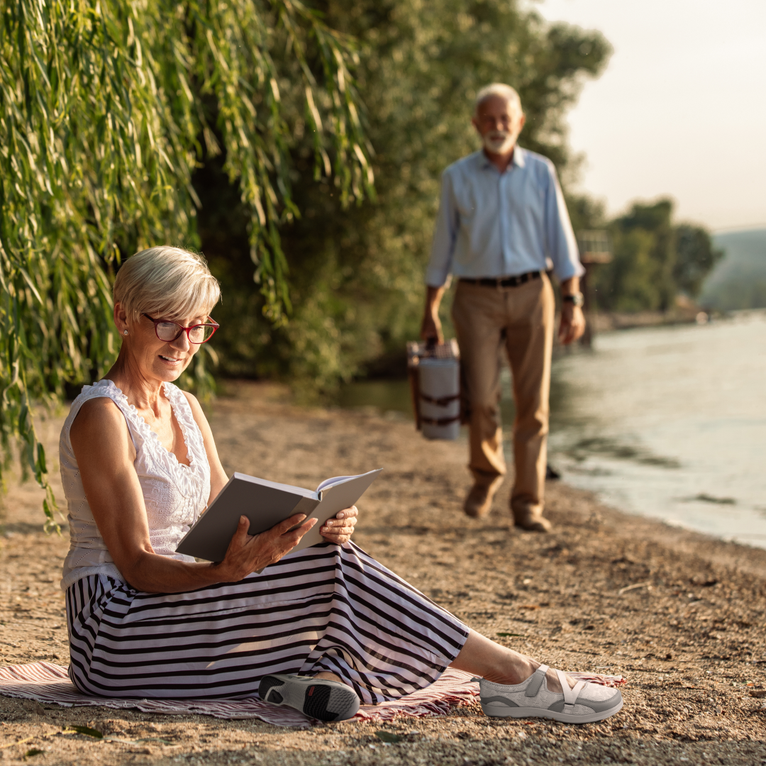 Woman sitting on beach reading book wearing Women's Orthopedic Mesh Mary Jane Casual Shoe - Grey Woman sitting on beach reading book wearing Women's Orthopedic Mesh Mary Jane Casual Shoe - Grey