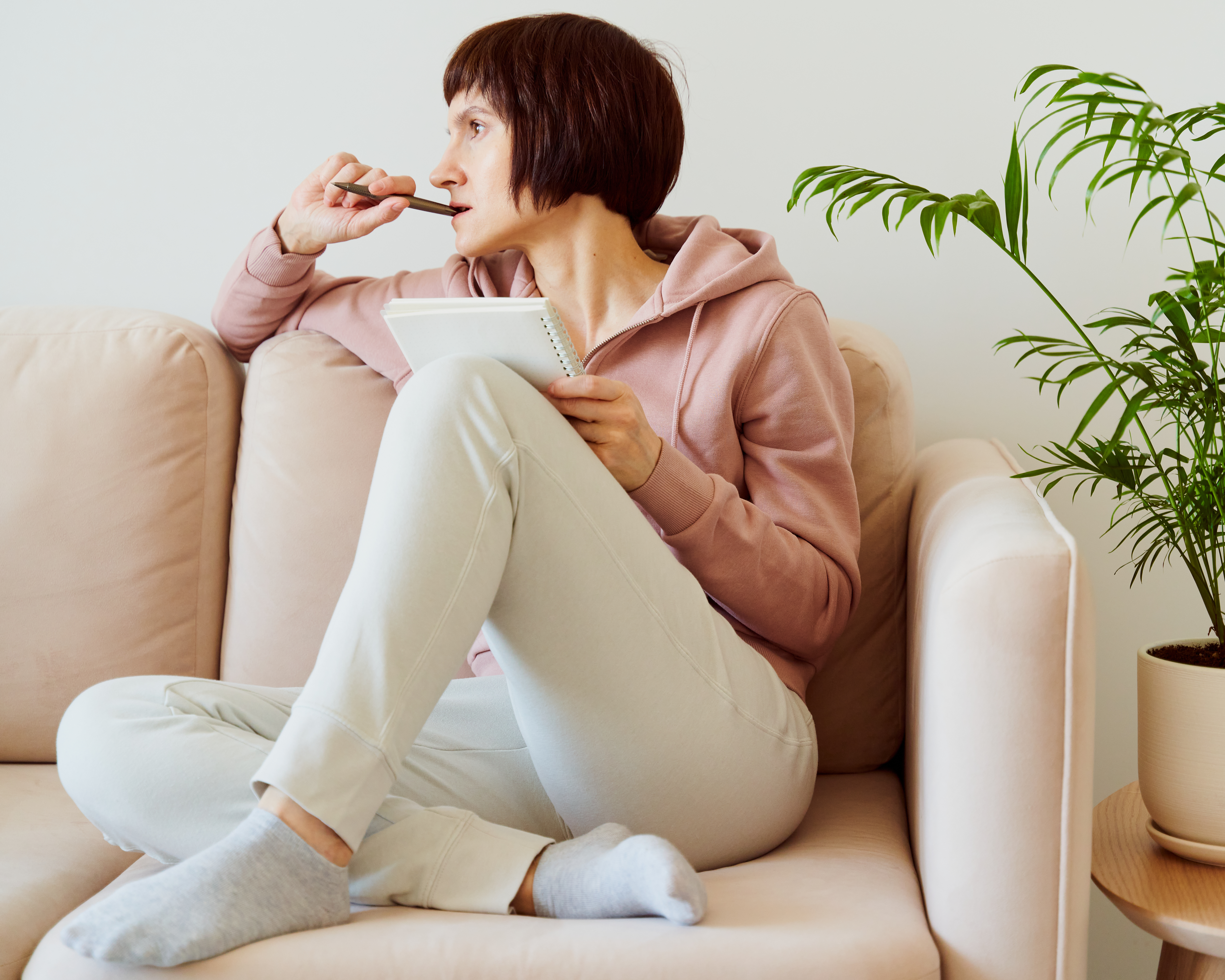 Woman with notepad in lap and pen in mouth self reflecting. Woman with notepad in lap and pen in mouth self reflecting.