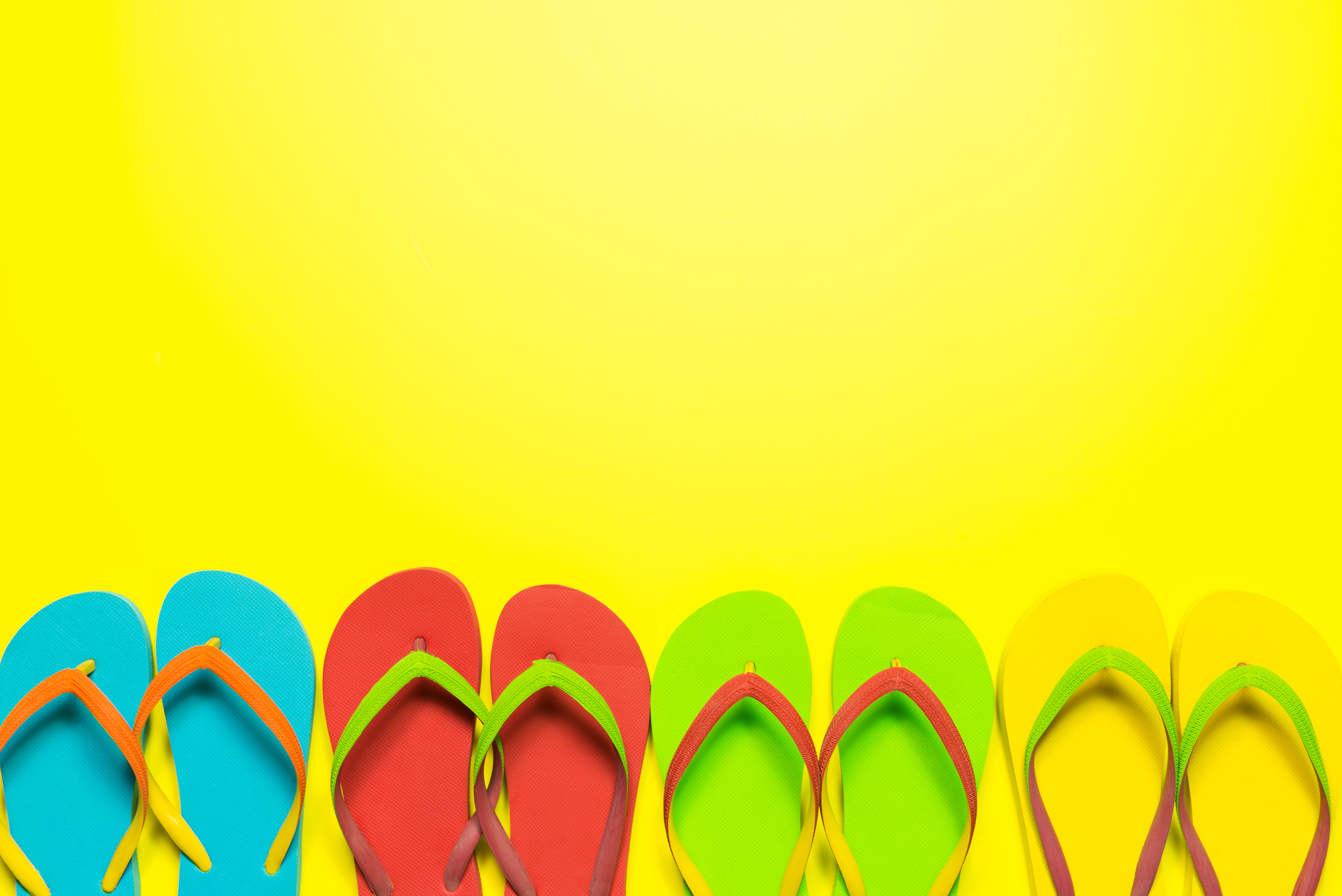 Multi-colored flip flops on yellow background Multi-colored flip flops on yellow background