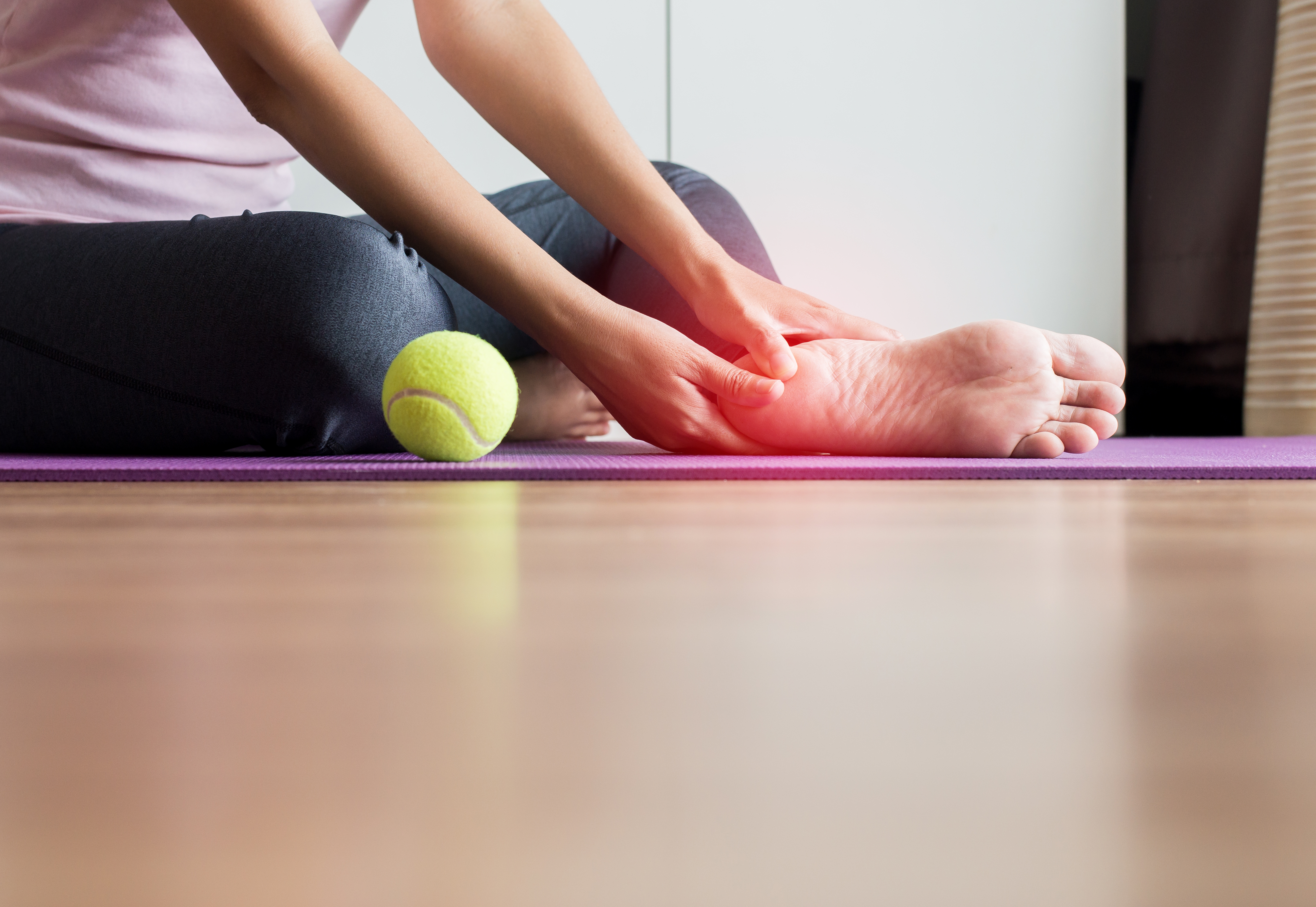 Woman holding foot in pain from Plantar Fasciitis Woman holding foot in pain from Plantar Fasciitis